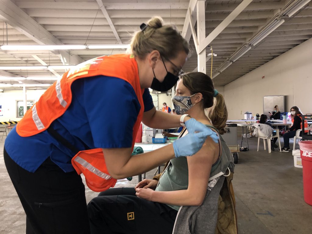 Nurse administering vaccine booster to another woman